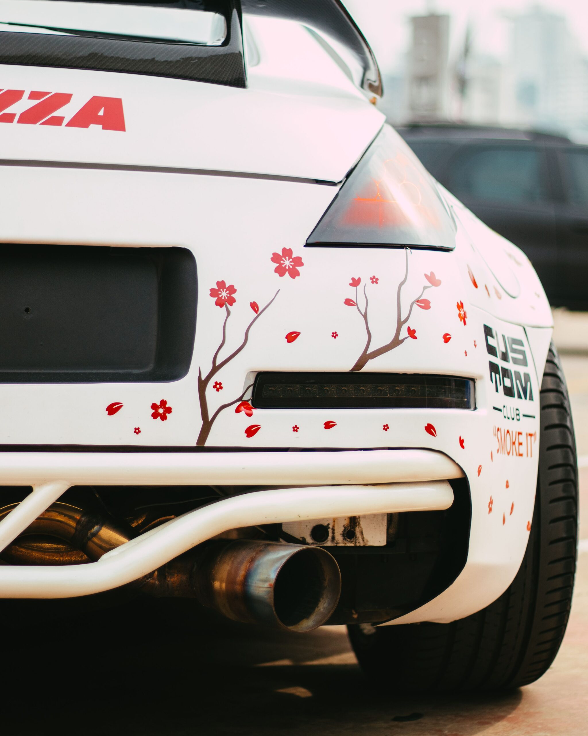 Rear view of a customized sports car featuring floral decals and a unique exhaust system.